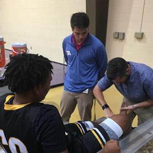 体育训练学生给篮球运动员的脚踝包扎
