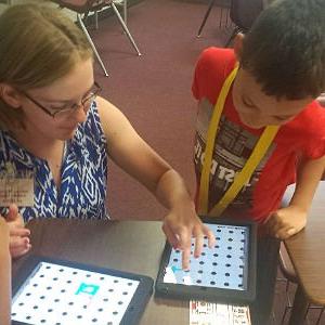special education teacher showing student how to engage with a game on an iPad