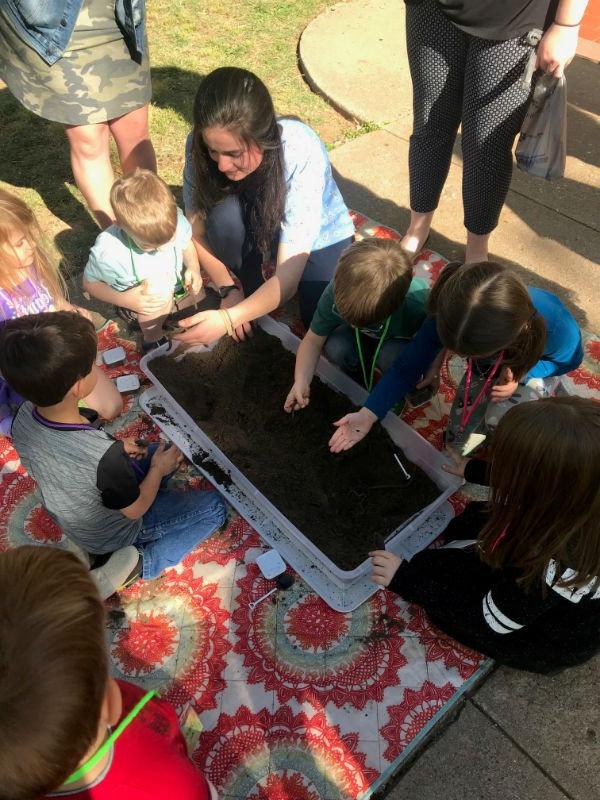 HSU student teacher and children playing in tub of dirt looking for worms