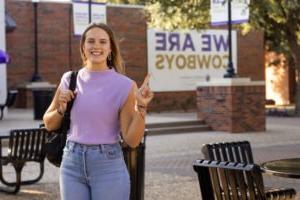 Sayler Beerwinkle in a purple shirt smiles on campus.
